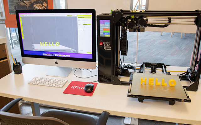 3D printing station with the word "Hello" being created