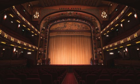 A theater interior featuring vibrant red seats and a grand curtain, creating an inviting atmosphere for performances.